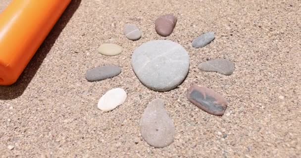 Láhev opalovací krém a sluneční kameny leží na písku 4k film — Stock video