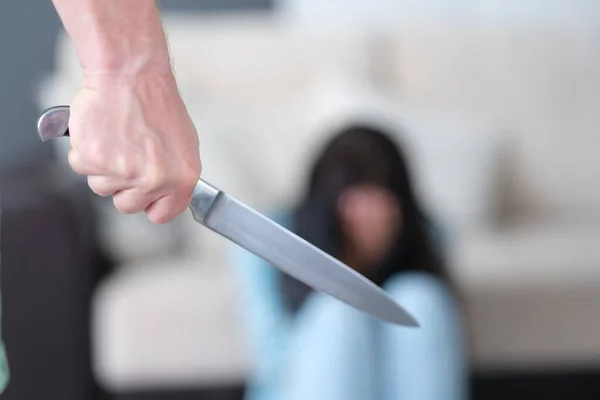 Homem agressivo segura faca na mão contra o fundo da mulher assustada — Fotografia de Stock