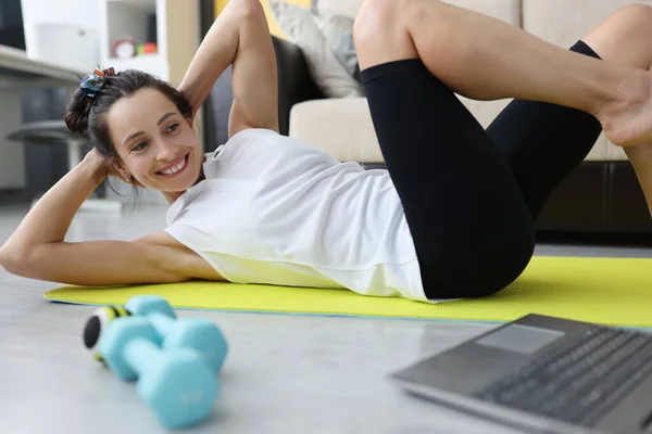 Jovem realiza exercícios esportivos para a imprensa do abdômen em casa no tapete — Fotografia de Stock