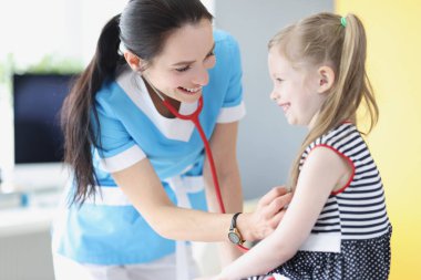 Pediyatrist klinikteki küçük kızın ciğerlerini ve kalbini dinliyor.