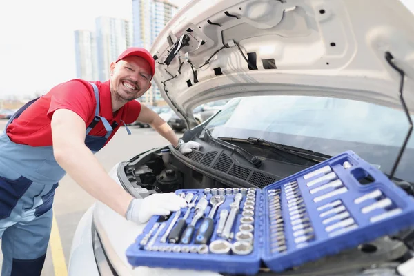 Smiling repairman in uniform fixing car with tools — Stock Photo, Image