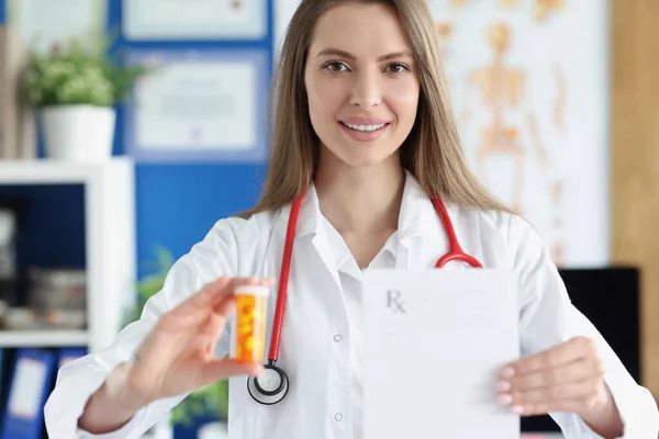 Médico sosteniendo frasco de medicamentos y prescripción en blanco en la clínica — Foto de Stock