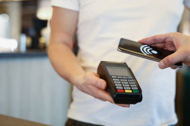 Ziyaretçi akıllı telefonu kullanarak ödeme işlemini yürütür.