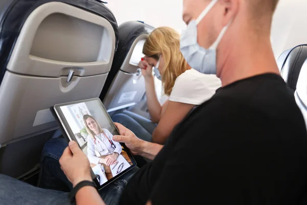 El hombre recibe consejo médico en videollamada mientras está sentado en el avión — Foto de Stock