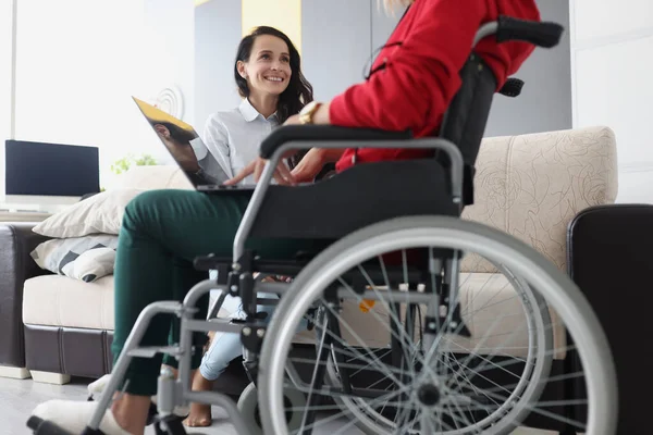 Жінка в інвалідному візку з ноутбуком спілкується з другом — стокове фото