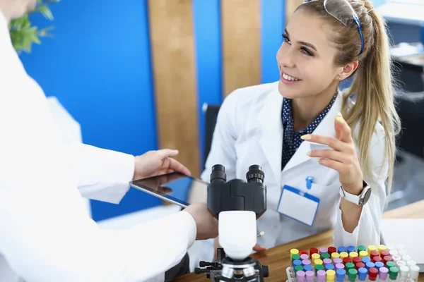 Assistant showing woman chemist information on digital tablet screen in laboratory — Stock Photo, Image