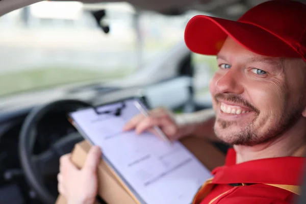 Portret van lachende mannelijke koerier chauffeur in autosalon met documenten — Stockfoto