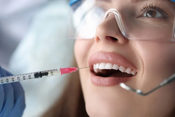 Retrato de jovem paciente sentada em cadeira de dentista com a boca aberta e recebendo uma injeção de anestésico — Fotografia de Stock