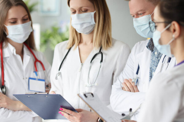 Team of doctors in medical protective mask examining the results of medical examination