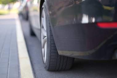 Otoparkta şeritleri ayıran arabanın önünde duruyor.