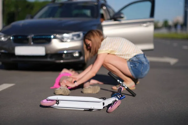 Niño scooter acostado frente a una niña pequeña lesionada en un accidente de coche de cerca — Foto de Stock