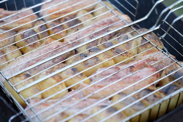 Carne de porco assada e batatas em rack de arame sobre fogo closeup — Fotografia de Stock