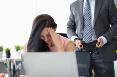 Depresyondaki kadın çalışma masasında oturuyor, erkek ayakta duruyor ve kemerini çözüyor.