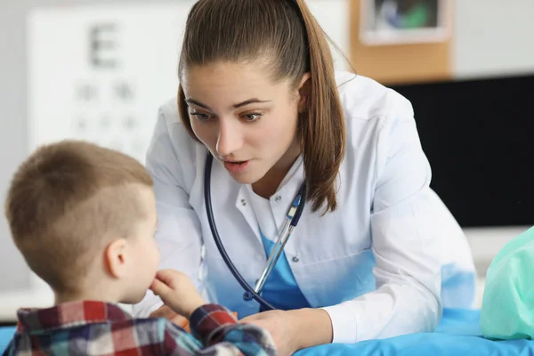 Küçük çocuk klinikteki kadın çocuk doktorunun randevusunda oturuyor. — Stok fotoğraf