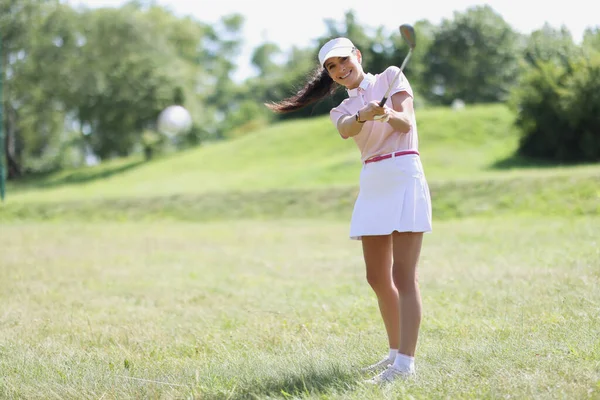 Jovem mulher de uniforme esportivo batendo bola com ferro no campo de golfe — Fotografia de Stock