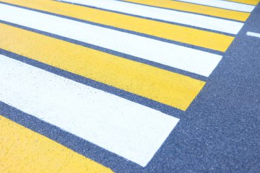 Gri asfalt zemin üzerinde beyaz ve sarı çizgilerin yakın plan