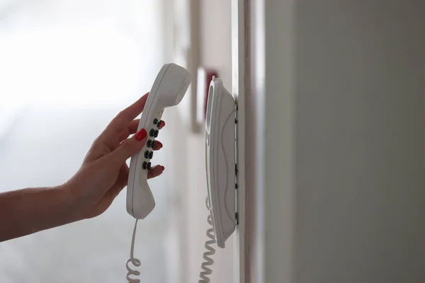 Mujer mano recogiendo el teléfono en el pasillo del hotel primer plano — Foto de Stock