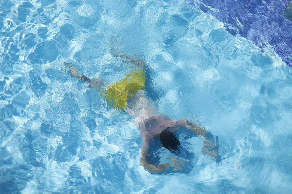 Young man lying on bottom of swimming pool top view — Stock Photo, Image