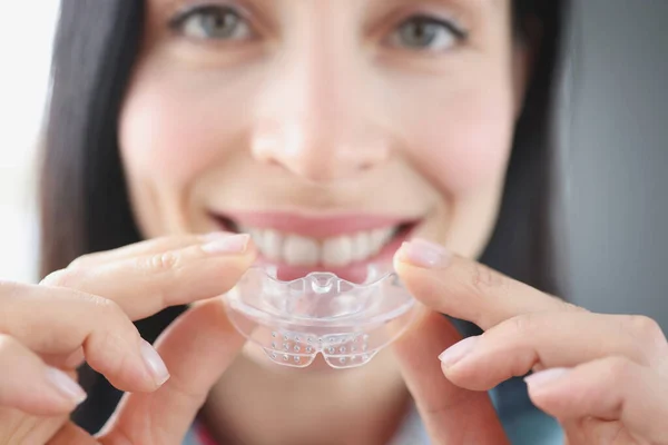 Gülümseyen kadın, dişlerini düzeltmek için temiz plastik ağız koruyucusu tutuyor. — Stok fotoğraf