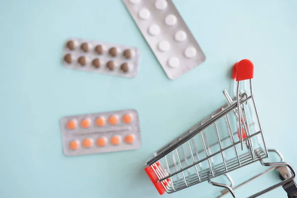 Blisters with pills lying near empty toy shopping basket closeup