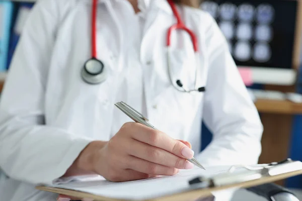 Lekarz pisanie w dokumentach medycznych na schowku w klinice zbliżenie — Zdjęcie stockowe