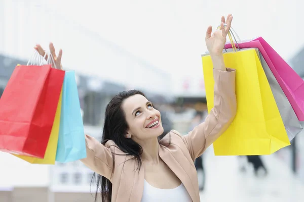 Junge Frau im Anzug nimmt viele bunte Papiertüten mit Einkäufen entgegen — Stockfoto