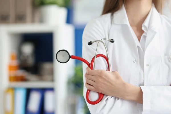 Woman doctor holding red stethoscope in clinic closeup — Stock Photo, Image