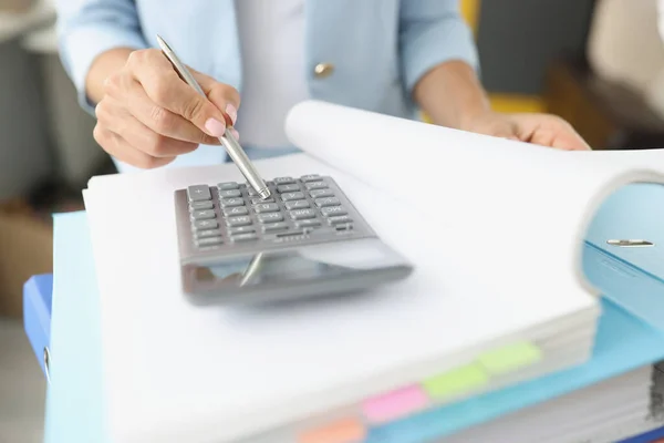 Woman leafing through folder with documents and looking at calculator closeup — Stock Photo, Image