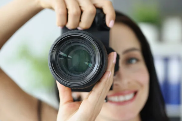 Joven sonriente mujer tomando fotos en negro profesional cámara de primer plano — Foto de Stock