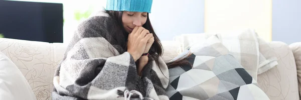 Femme congelée dans le chapeau et la couverture se trouve sur le canapé — Photo