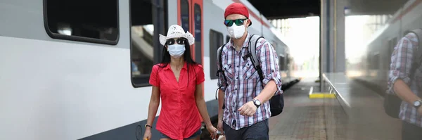 Tıbbi koruyucu maskeli kadın ve erkek istasyon platformu boyunca yürüyorlar. — Stok fotoğraf