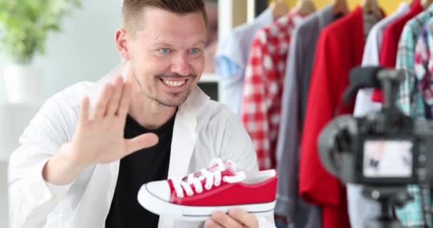 Enthusiastic male blogger demonstrates red sneakers to camera 4k movie — Vídeo de Stock