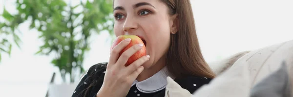 Portret van een jonge vrouw die in een appel bijt — Stockfoto