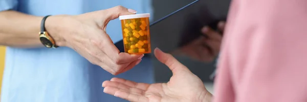 Лікар дає банку таблеток пацієнту крупним планом — стокове фото