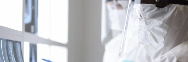 Лікарі в захисних костюмах дивляться на рентген в клініці — стокове фото