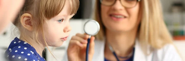 Mulher médico segurando estetoscópio perto de menina — Fotografia de Stock