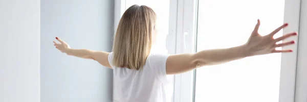 Mujer extendiendo sus brazos y de pie cerca de la ventana —  Fotos de Stock