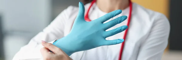 Glimlachende dokter doet handschoen om zijn hand — Stockfoto