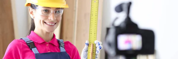 Kobieta budowniczy demonstruje linijkę na kamerze wideo — Zdjęcie stockowe