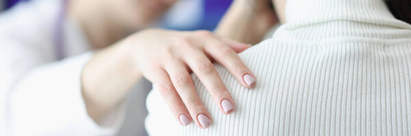 Physician holds upset patient shoulder sympathetically closeup