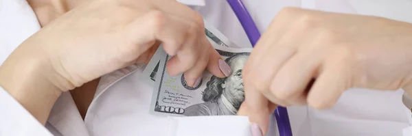 Doutor coloca nota de cem dólares em seu bolso — Fotografia de Stock