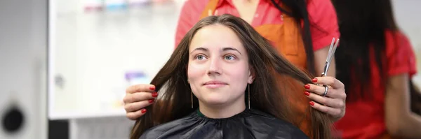 Maestro peluquero sostiene el cabello del cliente en salón de belleza — Foto de Stock