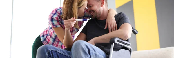 Glada kvinna och man i rullstol med graviditetstest — Stockfoto