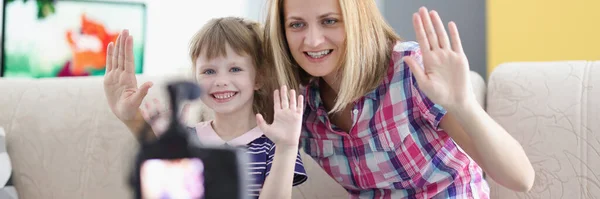 Fröhliche Mutter und Tochter halten ihre Hand zur Begrüßung vor die Videokamera — Stockfoto