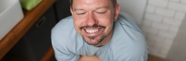 L'uomo con il sorriso soddisfatto siede sul water — Foto Stock