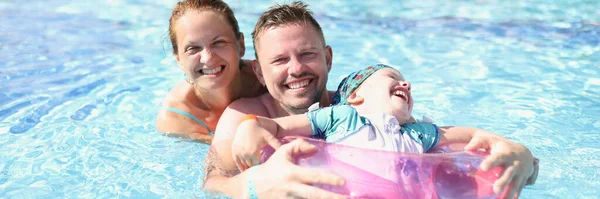 Family mom dad and daughter laugh and swim in pool