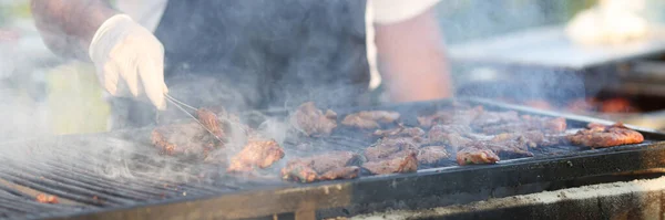 Szef kuchni rękawiczki zamienia mięso na grilla z szczypcami — Zdjęcie stockowe
