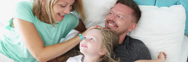 Pais e filhos mentem na cama rindo e abraçando. — Fotografia de Stock