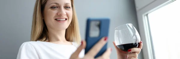 Femme avec un verre de vin regardant l'écran du téléphone — Photo