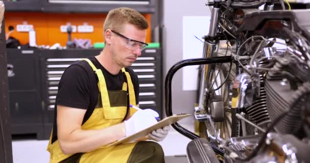 Mecânico masculino diagnostica peças em motocicleta no centro de serviço — Vídeo de Stock